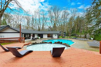 a backyard with a pool and a deck with chairs